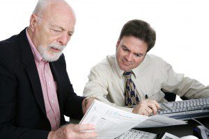 A senior man confused the his tax forms and seeking advice from an accountant. Isolated on white.