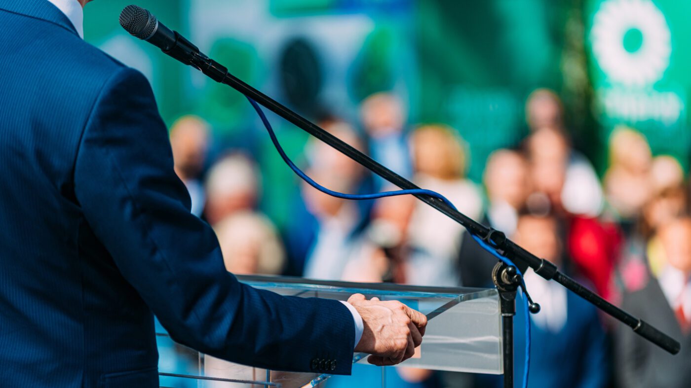 Political campaign. Unrecognizable politician on stage, speaking to the crowd during election campaign