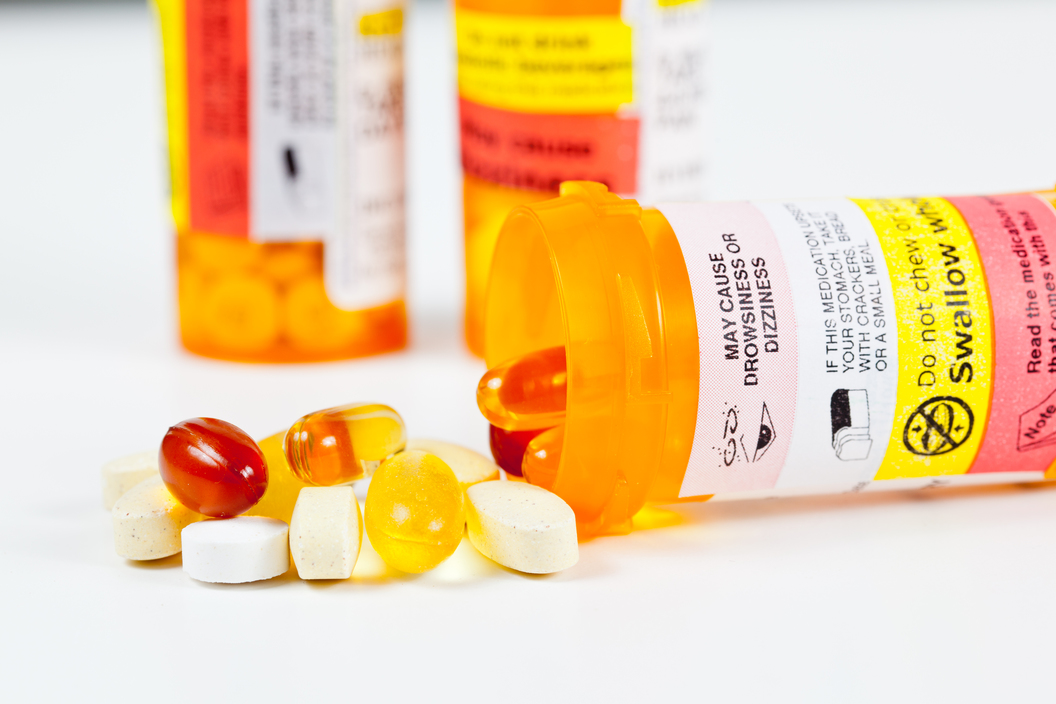 Colorful vitamins spilling from prescription bottle with warnings