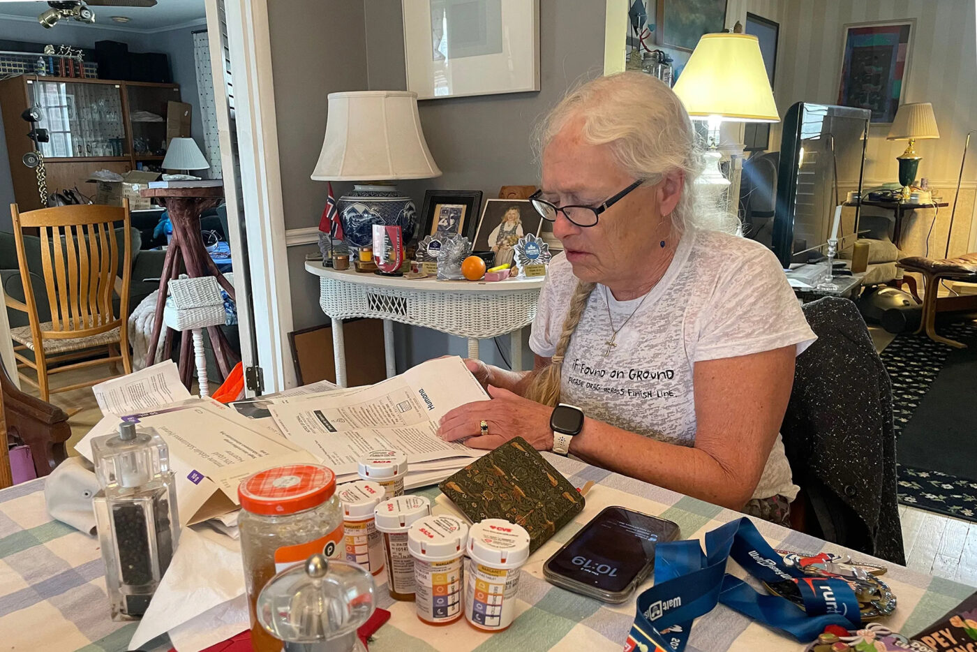 Weeks after Margaret Hvatum’s Humana Medicare Advantage plan denied coverage of a medicine she needs for a chronic condition, she was admitted to a hospital. Here Hvatum sits at her dining room table in her suburban St. Louis home sorting through letters from the insurer.