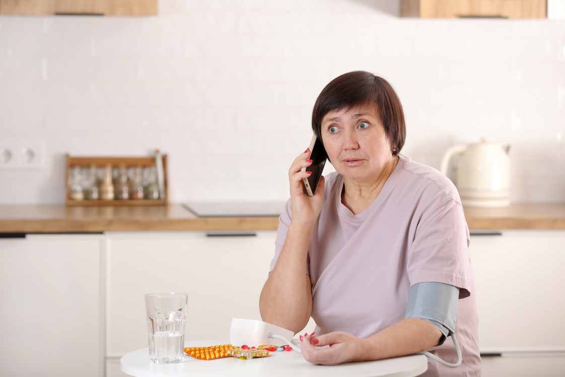 Online doctor consultation, remote medical assistance, seniors and healthcare. Sick elderly woman patient talking to doctor by cellphone, measuring blood pressure.