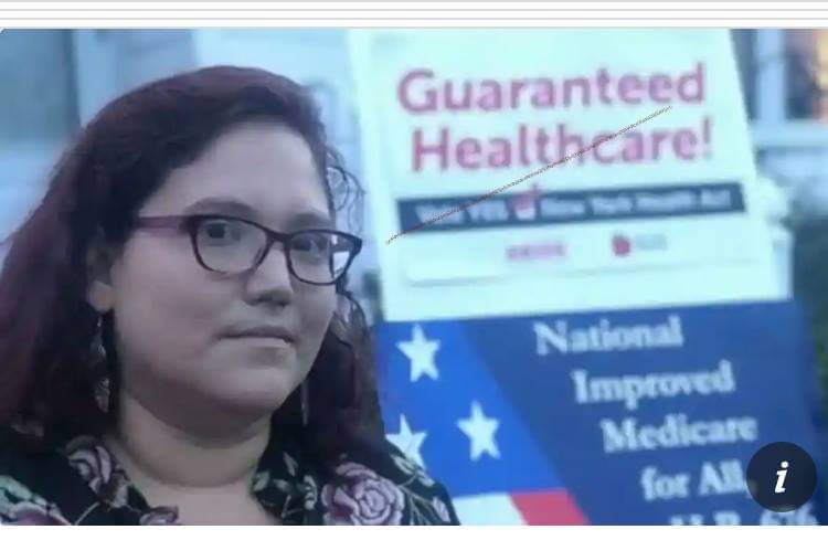 Mariana Pineda speaks at a healthcare justice rally in Albany, New York, wearing a face mask and using a rollator for support.