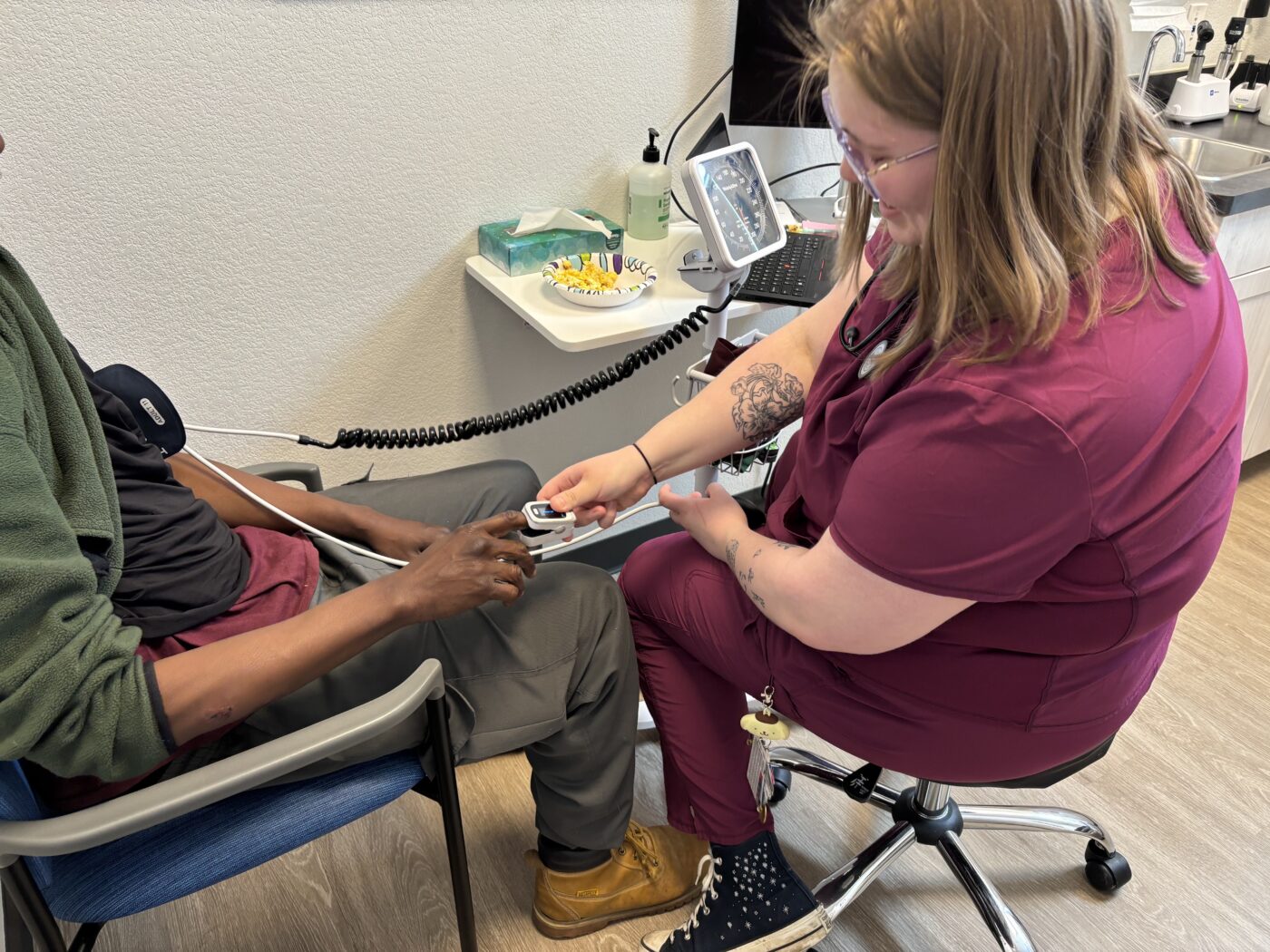 Izzy Kadrmas, a medical assistant at a clinic for people without stable housing in Missoula, Montana, tests Tywon Pugh’s blood oxygen saturation. Pugh has recurring seizures that make it hard to find a job, which worries him as Montana implements Medicaid work requirements.